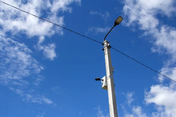 The LED street light is lined with a beautiful blue sky in the background with a video camera mounted on a pole. Video surveillance system.