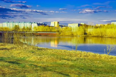 Batan güneşin ışınlarında Ivan Kaydalov'un setinin kenarından nehrin karşısındaki köprü. Saima Nehri üzerindeki parktan görünüm, Surgut, Rusya - 19 Mayıs 2019