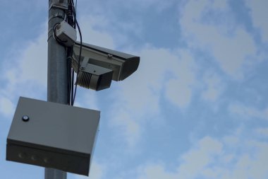 Güvenlik kamerası ve gardrop mavi gökyüzü ve bulutlara karşı şehirde bir kutup üzerinde. Kopyalama alanı