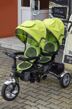 Mağazanın yakınındaki sokakta çift bebek arabası yeşil sarı. Üst ön görünüm. Surgut, Rusya - 12 Haziran 2109
