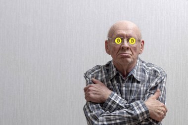 Gri arka planda gözlüklü yaşlı bir adam kollarını göğsüne geçirdi ve gözlüklerinin içinde bitcoin işaretine oturdu. Portre. Ön görünüm