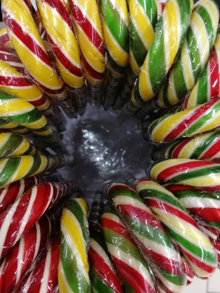 Multi-colored cane mint candy in the form of a cane in a round box.  View from above