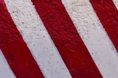 Yol yapım çalışmaları sırasında bir şehirde bir çit beton blok üzerinde eğimli kırmızı-beyaz çizgiler. Ön görünüm.