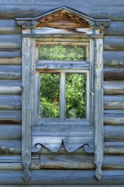Eski ahşap bir binanın üzerine oyulmuş bantlı pencere. Ön görüş. Dikey çekim.