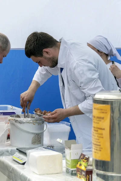 街头食品销售商从锅里挑出热腾腾的烤面包给买主吃 侧视图 Surgut Russia June 2019 — 图库照片