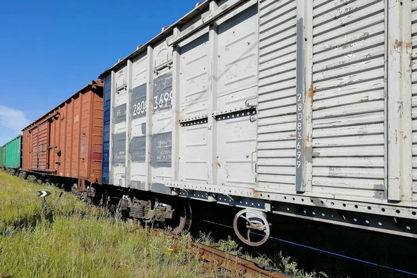 Rail cars on rails. Pictured along. Clear skies and a sunny day. A horizontal perspective.