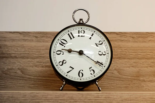 Relógio Alarme Fundo Branco Setas Pretas Uma Prateleira Madeira — Fotografia de Stock