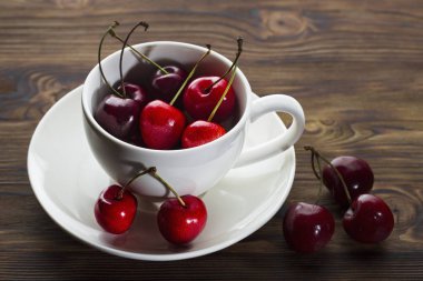 ahşap arka planda beyaz Kupası olgun yaz kiraz