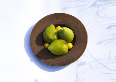 Beyaz bir arka plan üzerinde bir tabakta olgun incir ve erik