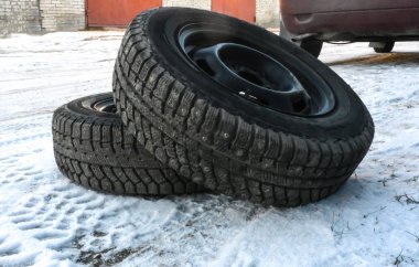 İki kış lastikleri disklerdeki yalan karla kaplı yere yanında