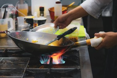 Şef bir tavada bir mutfak soba, soba pan ile Restoran mutfakta Şef üzerinde alev ile yemek yaparken gıda flambe