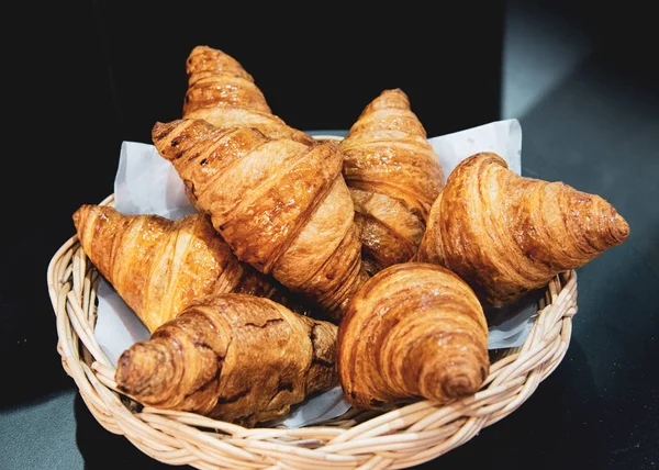 French croissants on wicker basket, bakery background