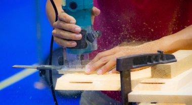 Bir marangoz atölyesinde ahşap tahta üzerinde elektrikli planya ile çalışma