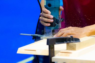 Bir marangoz atölyesinde ahşap tahta üzerinde elektrikli planya ile çalışma