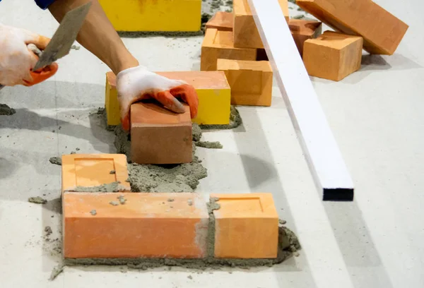 Bricklayer installing bricks, Bricklayer worker installing brick masonry on exterior wall with trowel putty knif