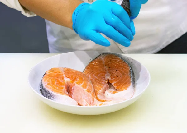 chef putting salt on salmon slice, Cropped of hands cooking salmon fish