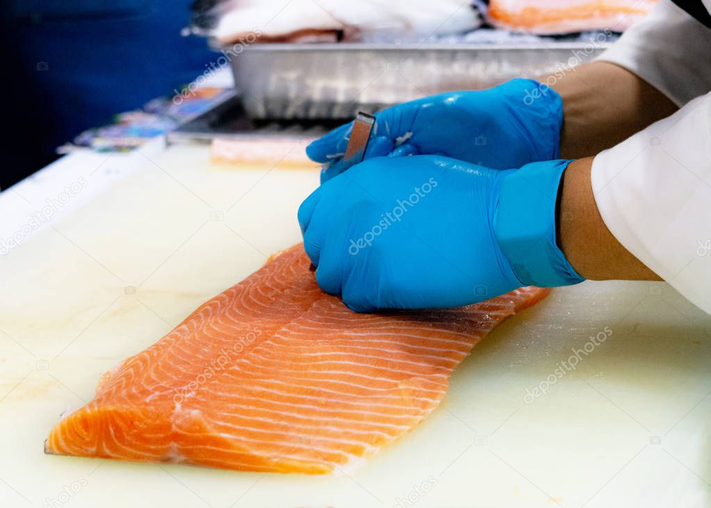 chef slicing raw fresh salmon, Chef preparing a fresh salmon on a cutting board