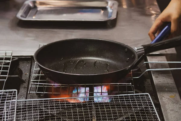 Шеф разливает масло в сковороду, шеф-повар готовит еду на кухне — стоковое фото