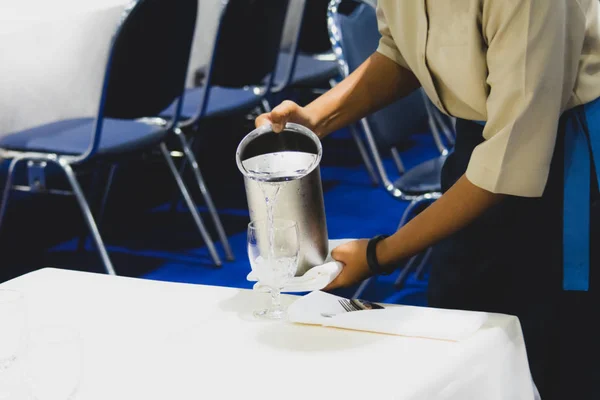 Waiter pouring water into glasses , Restaurants service