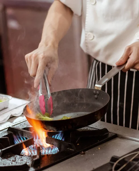 Chef memasak dengan api dalam penggorengan panci di atas kompor dapur — Stok Foto