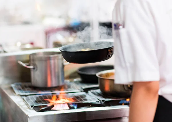 Chef cooking with flame in a frying pan on a kitchen stov — Stock Photo, Image