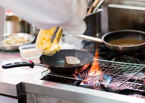 Шеф-повар готовит с пламенем в сковородке на кухонном столе — стоковое фото