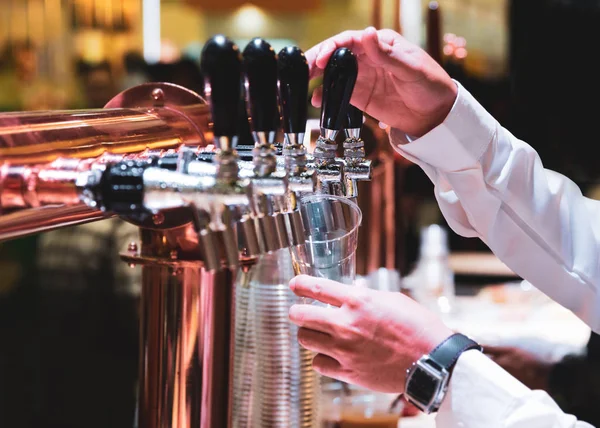 Bartender pouring draft beer in the bar, Barman hand at beer tap