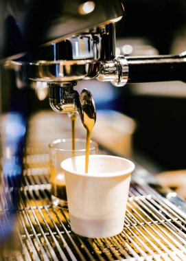 Espresso makinesi kahve demliyor. Kahve bardak içine dökülen i