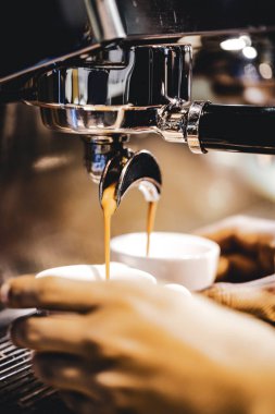 Espresso makinesi kahve demliyor. Kahve bardak içine dökülen i