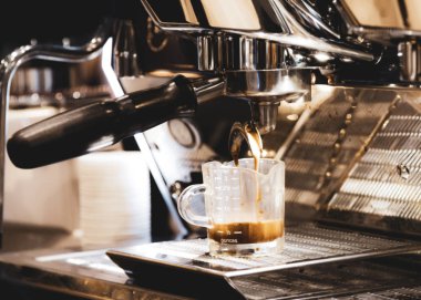 Espresso makinesi kahve demliyor. Kahve bardak içine dökülen i
