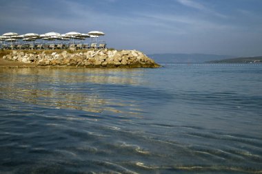 Beach Hırvatistan güzel manzara. Kristal berraklığında suları ve plaj şemsiyeleri. Island Krk.