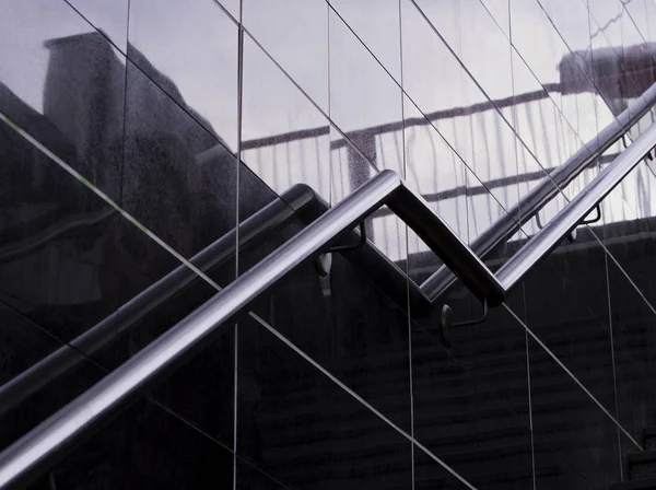 Merdiven paslanmaz çelik Küpeşte. Modern merdiven ile yeni modern Altgeçit paslanmaz çelik korkuluk. Yansıma ve cam duvar üzerinde gölgeler. Modern tasarım.