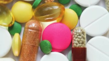 Beyaz bir yüzeyde renkli hapların ve kapsüllerin üst görünümü.