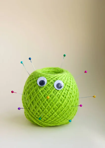 a tangle of green woolen threads with tailor\'s needles with beads, with eyes. cheerful cactus with their hands. handmade, needlework