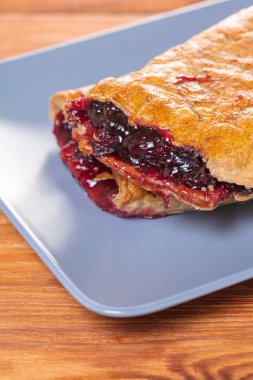 Ahşap arka plan üzerine bir tabak içinde fırın, vişne strudel