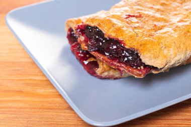 Ahşap arka plan üzerine bir tabak içinde fırın, vişne strudel