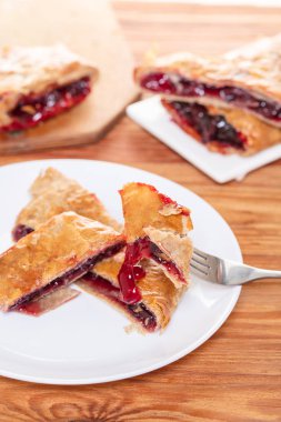 Ahşap arka plan üzerine bir tabak içinde fırın, vişne strudel