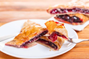 Ahşap arka plan üzerine bir tabak içinde fırın, vişne strudel