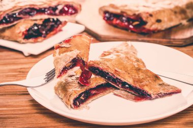 Ahşap arka plan üzerine bir tabak içinde fırın, vişne strudel