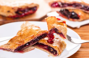 Ahşap arka plan üzerine bir tabak içinde fırın, vişne strudel