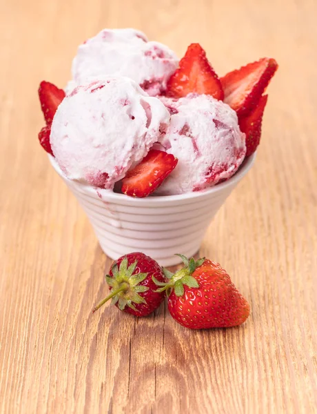 Strawberry ice cream in a bowl on wooden background