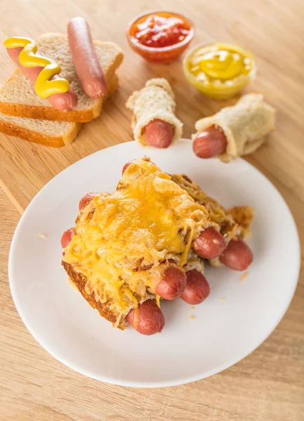 sausages in bread baked with cheese on a wooden background