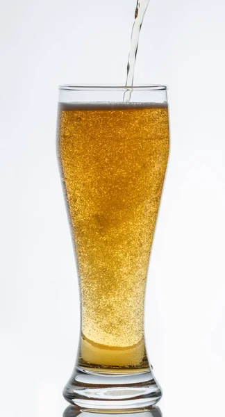 Light beer pours into a glass on a white background