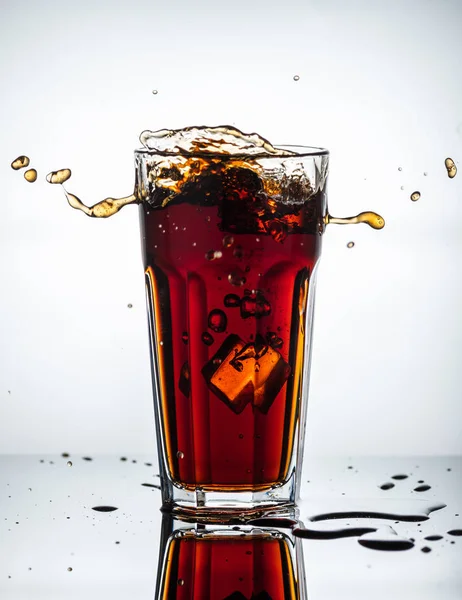 Splashes of drink from a glass with ice cubes