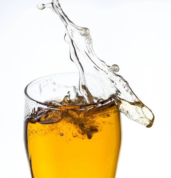 Splashing beer from a glass on white background