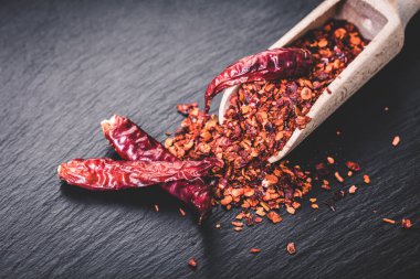 siyah arka plan üzerine bir kaşık kuru acı biber