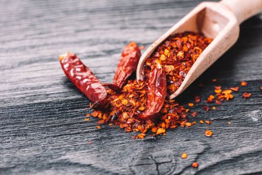 Siyah ahşap zemin üzerine bir kaşık kuru acı biber