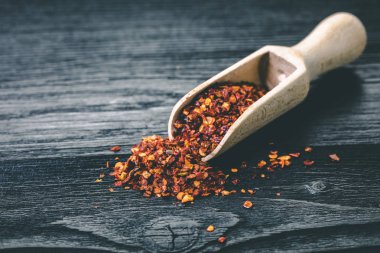 Siyah ahşap zemin üzerine bir kaşık kuru acı biber