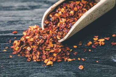 Siyah ahşap zemin üzerine bir kaşık kuru acı biber