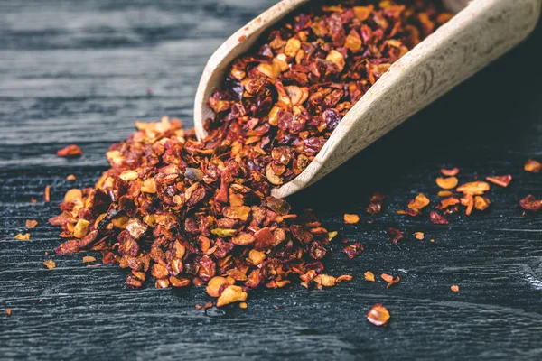 Siyah ahşap zemin üzerine bir kaşık kuru acı biber